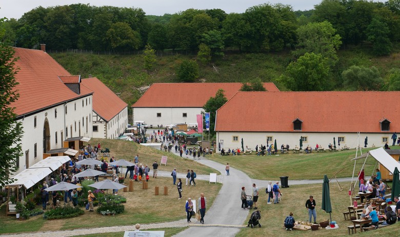 Ein Blick über das Gelände des Klosters Dalheim. Stände und Hütten des Klostermarktes sowie viele Besucher sind über das Gelände verteilt.