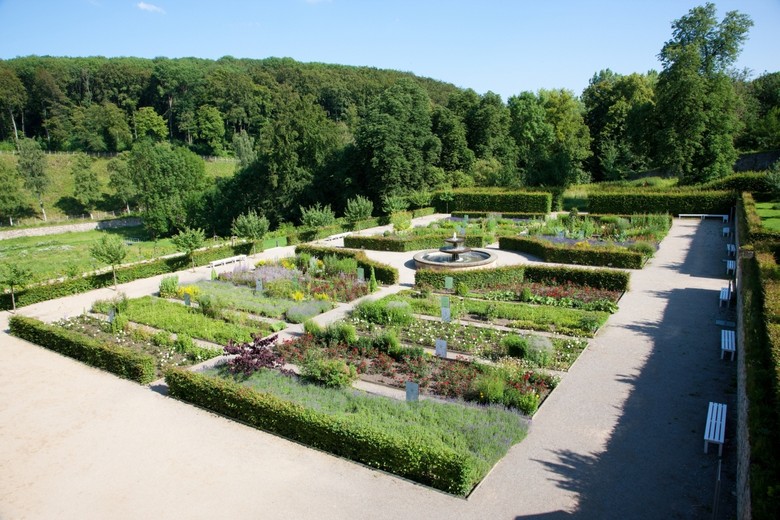 Garten mit kleinen Beeten, Hecken und einem Springbrunnen.